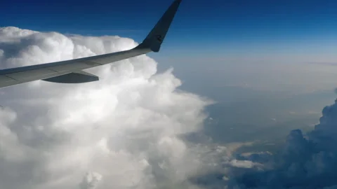 Airplane wing flying above fluffy white clouds in high altitude blue sky Vídeos de archivo 341974434