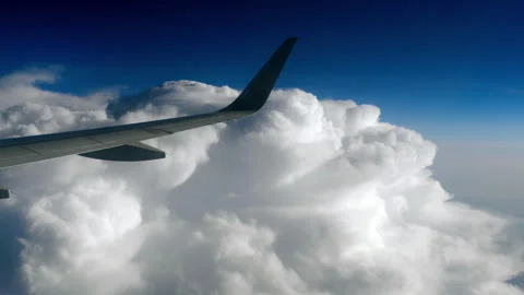 Airplane wing flying above thick white clouds in bright blue sky Video stock 340037563
