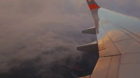 Airplane wing flying high above clouds during golden hour sunset Vídeo Stock 338144646