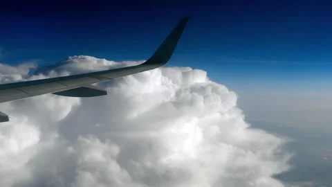 Airplane wing flying high above white clouds in blue sky Stockbeeldmateriaal 340920030