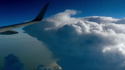 Airplane wing flying past massive cumulus clouds in sunny blue sky Stock-Footage 336678445