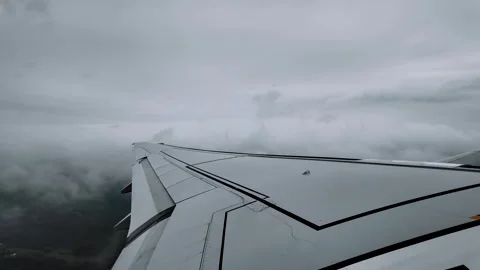 Airplane wing flying through dark grey storm clouds Видео 330700025
