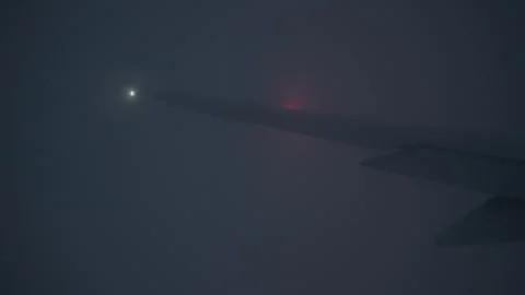 Airplane wing flying through thick night fog with flashing navigation lights Stock Footage 325050029