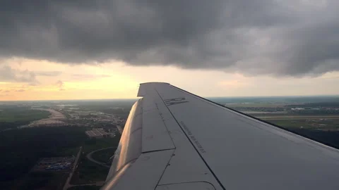 Airplane wing frames view of ground below as commercial aircraft. Whether it Stock Footage 252539132