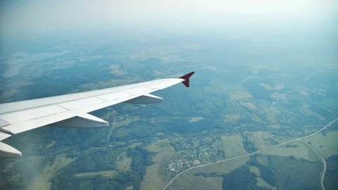 Airplane wing hovering over verdant countryside, revealing patchwork fields 動画素材 310827997