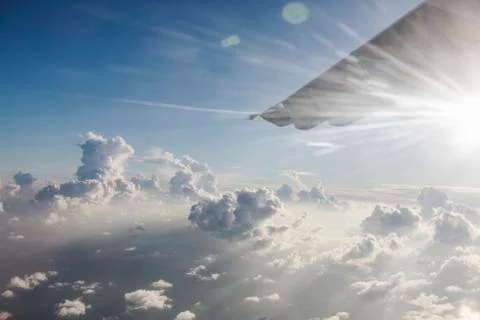 Airplane wing moving through tranquil, sunny, cloudy sky Stock Photos