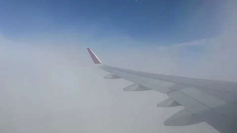 An airplane wing with a red tip extends over dense clouds Stock Footage 305033134