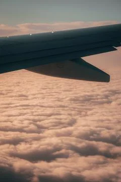 Airplane wing soaring above clouds, a sublime moment where the Earth fades .. Stock Photos