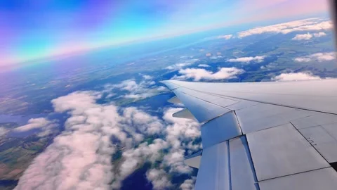 Airplane wing soaring above fluffy clouds under a vibrant sky at high altitude Stock Footage 288934979