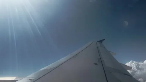 Airplane wing soaring above thick white clouds in bright blue sky with dram.. Stock Footage 337484964