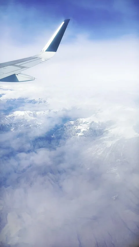 Airplane Wing Soaring Through Clouds with Stunning Mountain View Stock Footage 329886167