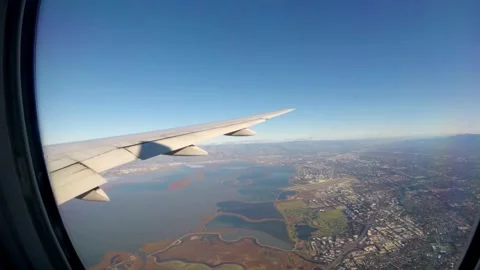 Airplane wing soars above the landscape on a sunny day Stock Footage 312678379