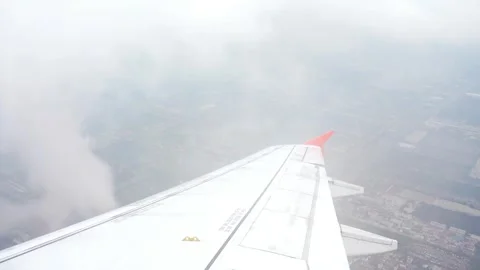 Airplane wing soars through fluffy white clouds in the bright blue sky Stock Footage 312432837