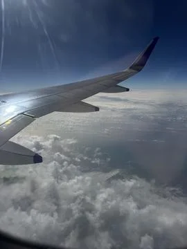 Airplane wing stretching over sunlit clouds, smooth daytime flight, digital.. Stock Photos