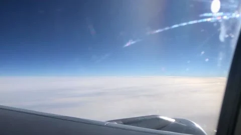 Airplane wing through the porthole. Flying above the clouds on an airplane. View Vídeos de archivo 201890534