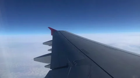 Airplane wing through the porthole. Flying above the clouds on an airplane. View Video stock 201890551