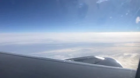 Airplane wing through the porthole. Flying above the clouds on an airplane. View Vídeos de archivo 201890568