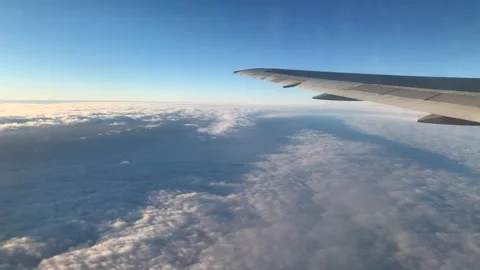 Airplane wing view above clouds in blue sky during flight Stock Footage 345213281