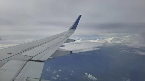 Airplane Wing View Above Clouds During Flight Over Ocean Stock Photos