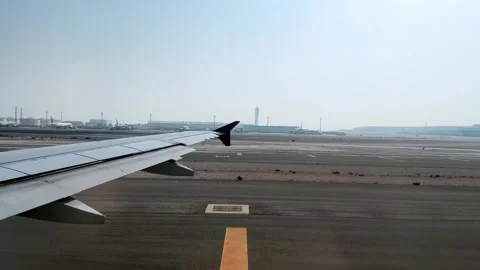 Airplane wing view on runway at arrival near terminal and control tower at Do Stock Footage 305943825