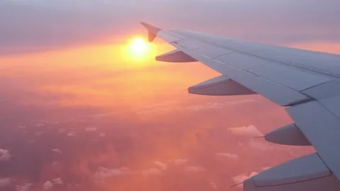 Airplane wing view at sunset over a purple and pink cloud layer. Stock Footage 297538125