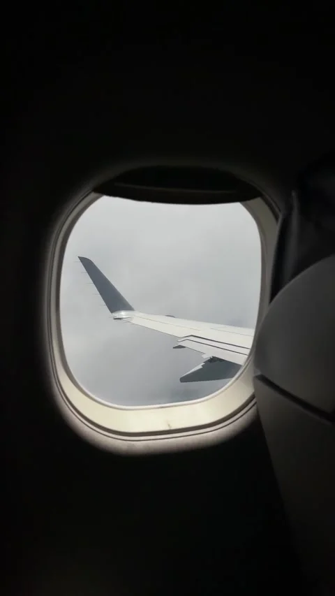 Airplane Wing View Through Passenger Window as it Flies Through Clouds. Shaky Ha Vídeos de archivo 345016205