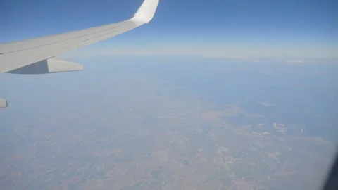 Airplane wing view through the window at high altitude with vast landscape .. Stock Footage 286333279