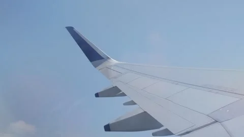 Airplane Wing View Through Window During a Turbulant Flight With Passing Clouds Stock Footage 334961359