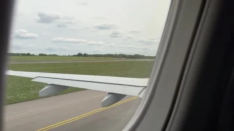 Airplane wing view while taxiing on runway at Vilnius airport under cloudy sky Stock Footage 310784674