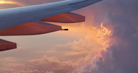 Airplane wing visible through window against clouds at sunset Stock Footage 331651432