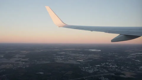 Airplane wing with winglet flying over rural landscape during pastel sunrise Stock Footage 325049864