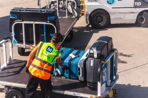 Airport Baggage Handler Loading Suitcases onto Ground Cart Stock Photos