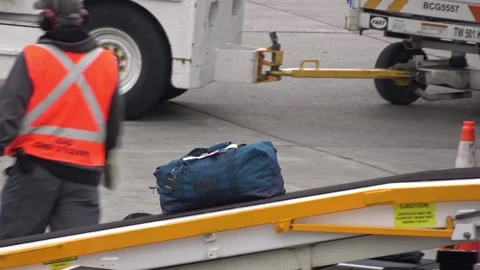 Airport ground crew loading a duffel bag onto the plane's conveyor system. Stock Footage 339647298