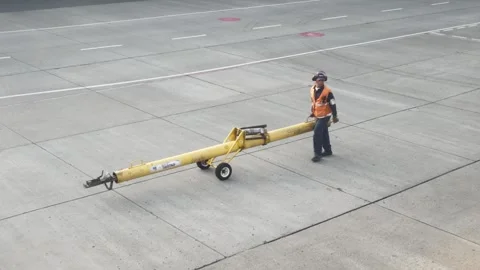 Airport ground crew worker walking with tow bar on tarmac Vídeos de archivo 334935608