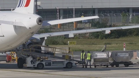 Airport ground support - workers move luggage from belt to luggage cart v2 Stock Footage 119830973