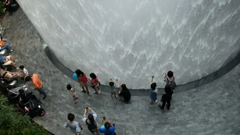 Airport passengers in Rain Vortex waterfall, Jewel Changi Airport, Singapore 스톡 동영상 110436611