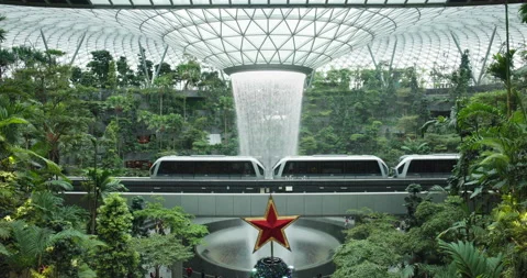 Airport train pass iconic rain vortex waterfall in Singapore rainforest; Stock Footage 223374294