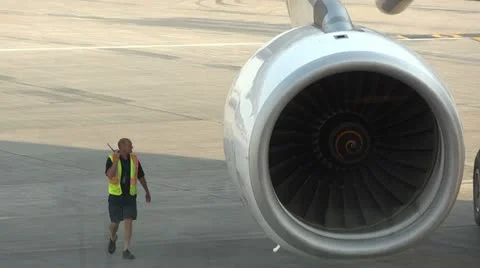 Airport Worker Walks on the Tarmac Near a Plane Reactor Stock Footage