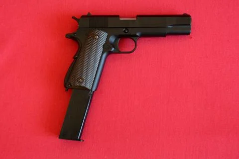 Airsoft gun and magazine on red fabric. Stock Photos