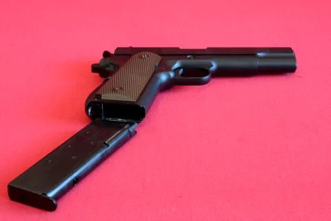 Airsoft gun and magazine on red fabric. Stock Photos