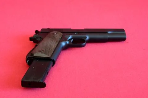 Airsoft gun and magazine on red fabric. Stock Photos