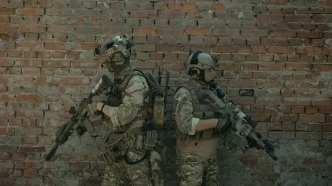 Airsoft men back to back look around the corner with gun. Urban territory. Video stock 127884131