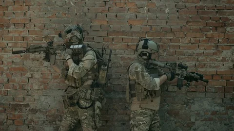 Airsoft men back to back look around the corner with gun. Tactics rules Video stock 127884134
