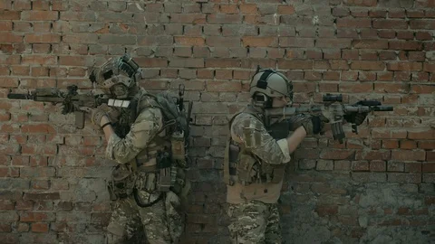 Airsoft men back to back look around the corner with gun. Tactics rules Video stock 127884140