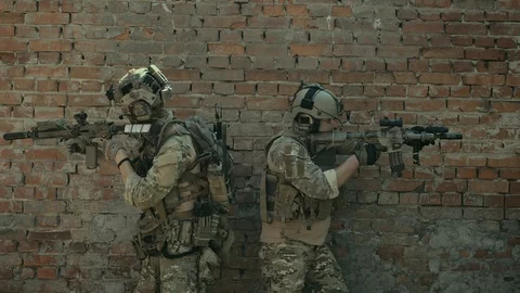 Airsoft men back to back look around the corner with gun. Urban territory. Stock-Footage 127884155