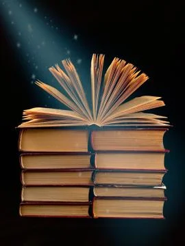Ajar pages in the book. A stack of old hardback textbooks, on a black backgro Stock Photos
