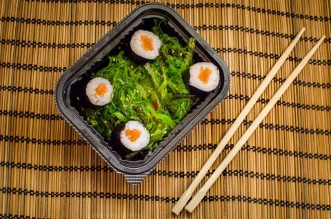 Ake away sushi dish with algae with chostick and wooden cloth background Stock Photos