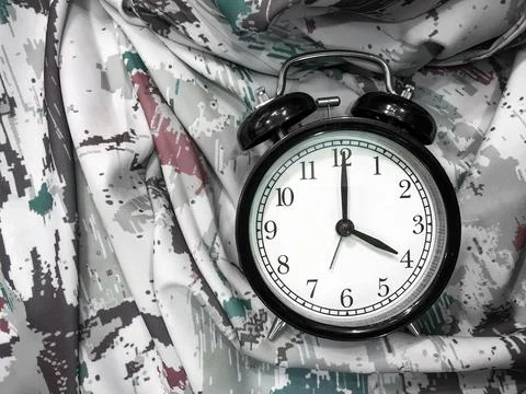 Alarm Clock at 4 O'clock with Abstract Fabric Background Foto stock