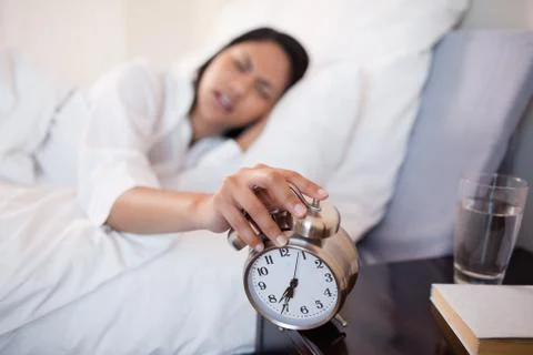 Alarm clock almost falling off the bedside locker while being turned off Stock Photos