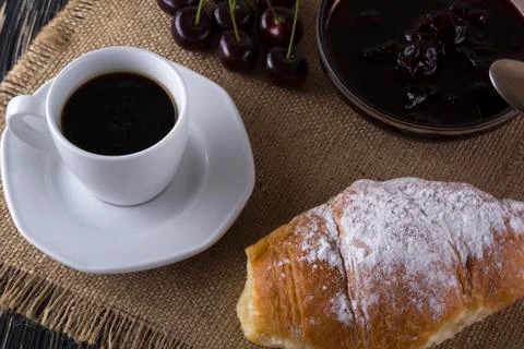Alarm clock and breakfast with cherry jam, coffee , croissant. Stock Photos